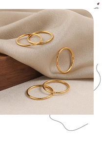 Detalle de cinco anillos apilables bañados en oro con circonitas sobre fondo de seda