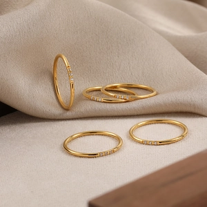 Set de cinco anillos minimalistas bañados en oro con tres circonitas para apilar cada uno