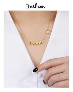 Close-up of golden daisy flower necklace on neck with six small floral charms