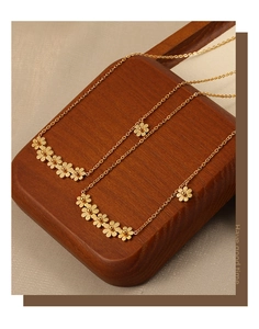 Close-up of golden daisy necklaces with matte and polished petals on wooden base