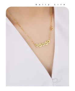Close-up of golden daisy pendant necklace worn by model showing six small flowers