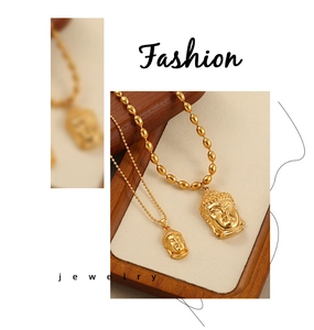 Détails de deux pendentifs tête de bouddha dorés sur un support bijoux élégant