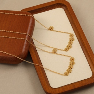 Elegant gold plated titanium daisy necklace featuring six small floral pendants on wood