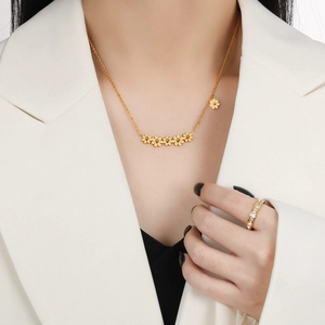 Golden six-daisy pendant necklace in titanium steel worn with a professional white blazer