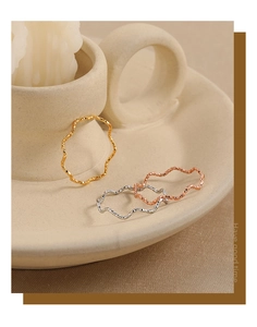 Detail van gedraaide golfringen in goud, zilver en roségoud met een gehamerde textuur