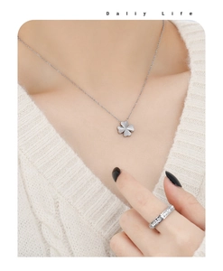 Vue détaillée du collier trèfle et de la bague en argent sur pull en tricot