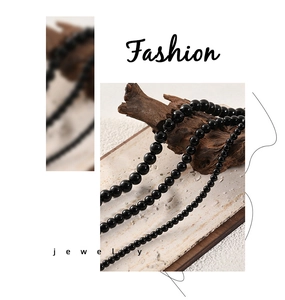 Detailed view of three polished black onyx bead necklaces displayed on rustic stone and wood