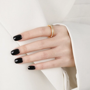 Eternity gold ring with square cubic zirconia diamonds worn on hand with white blazer