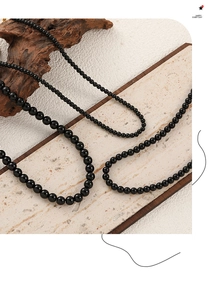 Detail view of round black onyx bead necklaces in various sizes on natural stone background