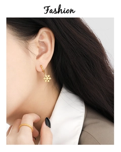 Nahaufnahme goldener Schneeflocken-Ohrringe und passender Ring an einem Model für Eleganz