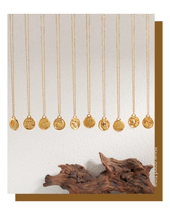 Vertical display of 24K gold plated zodiac coin necklaces on vintage wood background