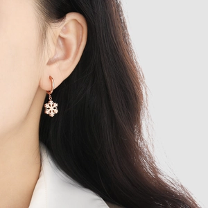 Elegante roségoldene Schneeflocken-Ohrringe am Modell mit schickem Winter-Design