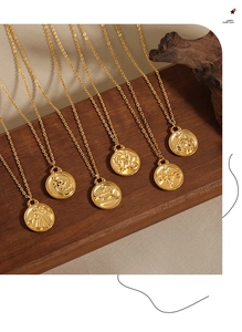 Detail view of 24K gold plated zodiac coin necklaces on a rustic wooden display stand