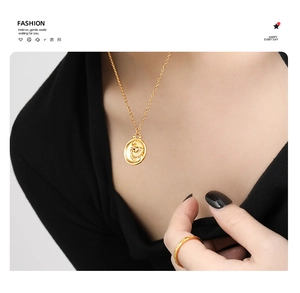 Detail of 24K gold plated zodiac pendant necklace and ring on a model with black clothing
