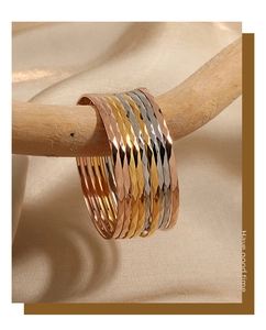 Détail de joncs géométriques 3mm en or et argent sur une branche en bois naturel