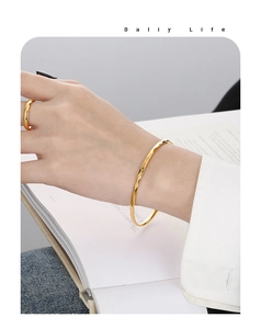Détail d'un bracelet doré de 3mm avec motif losange et bague portés par un modèle