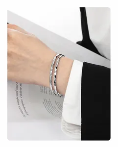 Détail d'un bracelet double épaisseur argenté avec facettes losanges sur le poignet