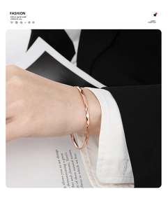 Détail du jonc en or rose à facettes losanges au poignet avec une tenue de bureau