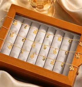Detailansicht von Gold-Kleeblatt- und Glocken-Fußkettchen in einer hölzernen Schmuckbox