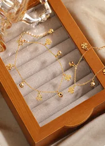 Detailansicht von goldenen Kleeblatt- und Glockenanhängern auf einem feinen Fußkettchen