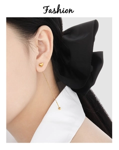 Close-up of golden heart pendant threader earrings on a model with elegant black satin bow