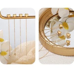 Detail of gold heart pendant drop earrings with elegant thin metal chain on a display