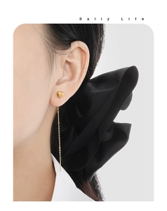 Detail shot of heart-shaped gold ear threader on model with long chain and bar