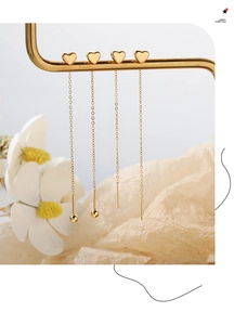Detail of gold heart long chain threader earrings with delicate bead and needle design