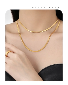 Détail de chaînes serpent dorées superposées et d'une bague matelassée sur mannequin