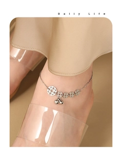 Detailed view of silver anklet featuring five coins and jingling bell pendants on ankle
