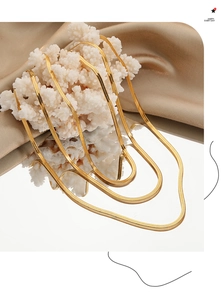 Vue détaillée de colliers en maille serpent dorée superposés sur un tissu en soie