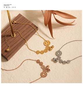 Detail of vintage gold anklet with five coins and bells on a rustic wooden stand