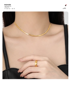 Vue détaillée d'un collier chaîne serpent dorée et d'une bague à motif matelassé sur modèle