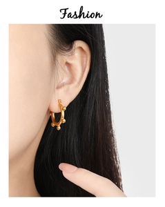 Close-up of minimalist gold hoop earrings with small bead accents on a model ear