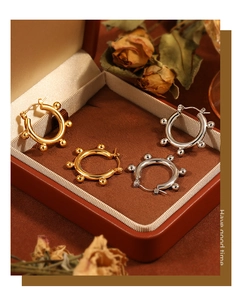Detail view of gold and silver bean hoop earrings displayed in a luxury brown velvet case