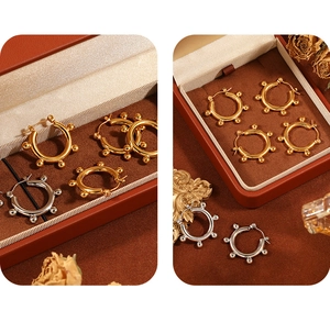 Detailed view of gold and silver bean hoop earrings on a vintage jewelry box setup
