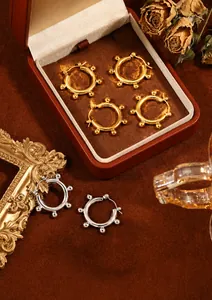 Detailed view of minimalist gold and silver hoop earrings with bead accents on velvet