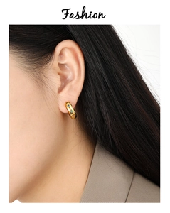 Close-up of gold hoop earring with colorful zircon stones on a model's ear