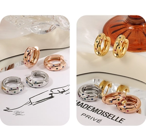 Detailed close-up of chunky gold hoop earrings with colorful inlaid zircon star patterns