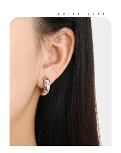 Close-up of a silver earring with colorful zircons worn on a female model