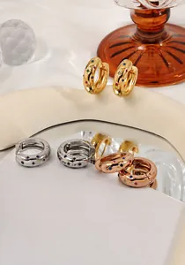Detail of gold hoop earrings with multi-colored gemstones and reflective glass display