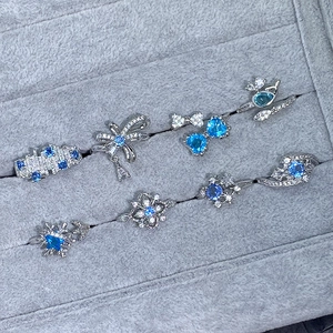 Détail de bagues argentées avec zircon bleu et nœud dans un coffret à bijoux gris