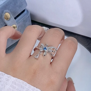 Détail d'une bague nœud argentée avec zircon bleu et pendentif en forme de goutte d'eau
