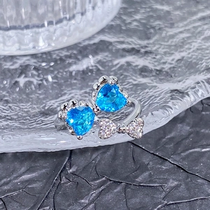 Détail de la bague ajustable avec pierres de cœur bleues et noeud serti de zircons