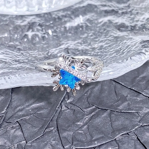 Détail macro d'une bague étoile en argent avec zircon bleu mer et motif flocon de neige