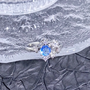 Macro d'une bague avec zircon bleu et petits diamants sur un plateau en verre