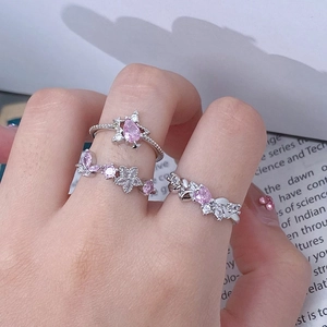 Detailed view of silver rings featuring pink teardrop stones and butterfly motifs