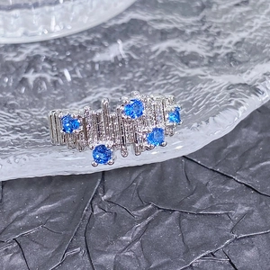 Vue macro d'une bague argentée avec texture irrégulière et cinq zircons bleus