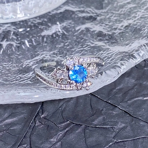 Vue macro d'une bague ouverte en argent avec gemme bleue et détails de nœud étincelants