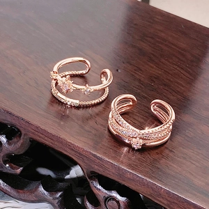 Dettaglio di anelli multistrato in oro rosa con zirconi brillanti su legno scuro
